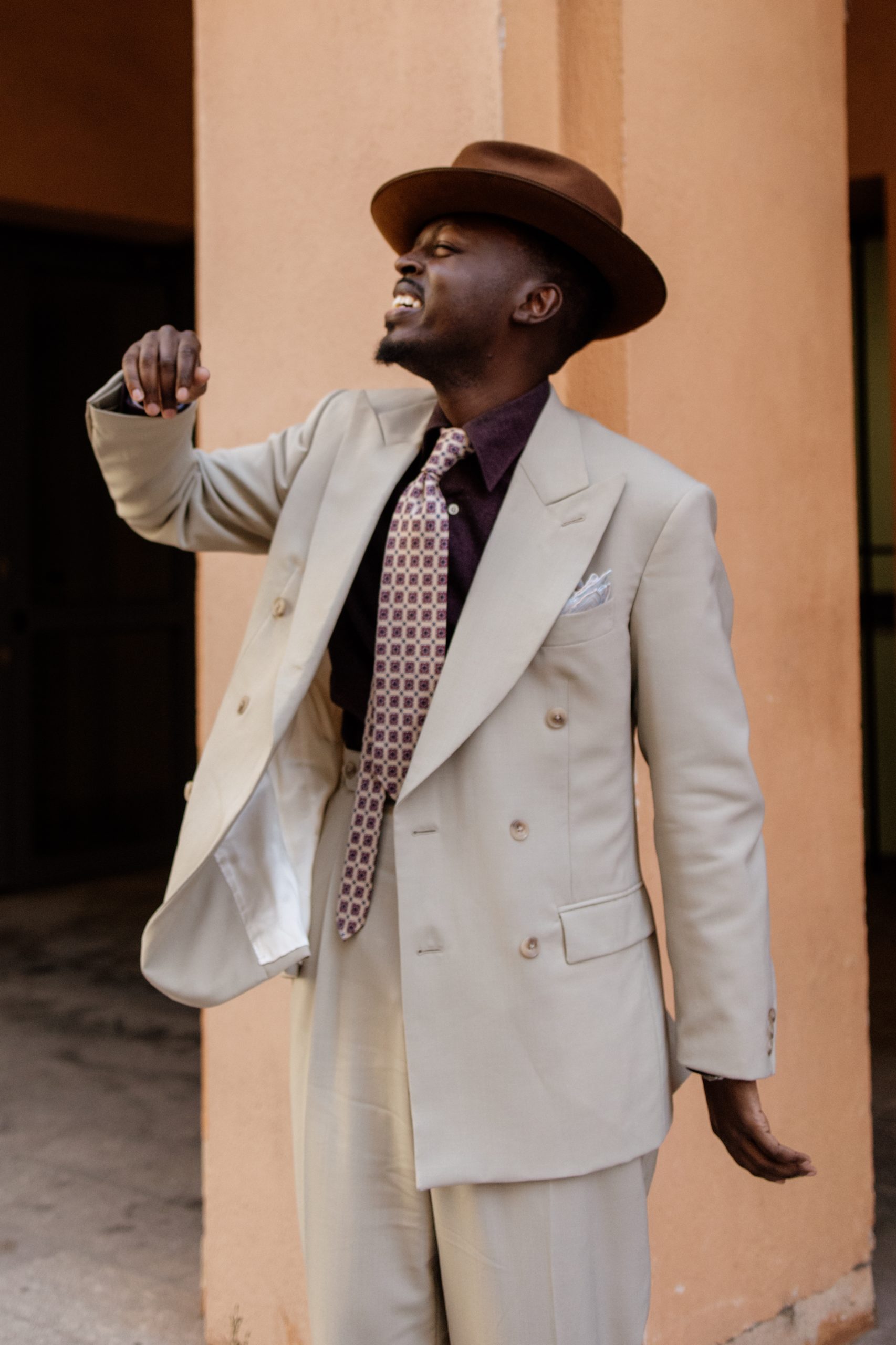 Image descriptive de Kevis Manzi portant un costume beige.